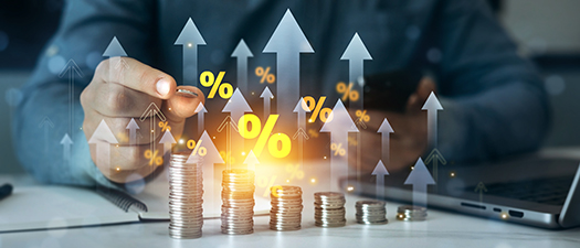 Foto: Mehrere Münzstapel mit Pfeilen die in die Höhe zeigen sowie mehrere Prozentzeichen