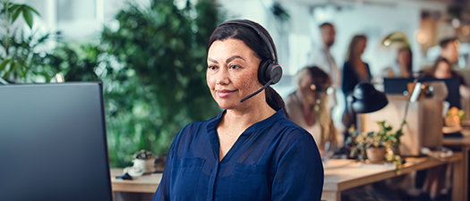 Bildbeschreibung: Frau sitzt mit Headset vor einem Bildschirm