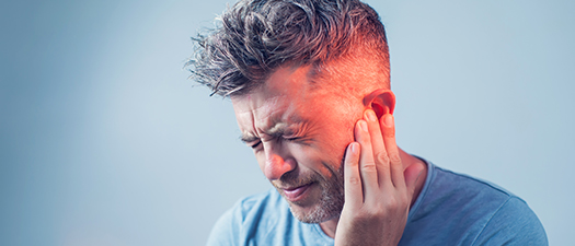 Bildbeschreibung: Ein Mann fasst sich ans Ohr. Er hat Tinnitusbeschwerden.