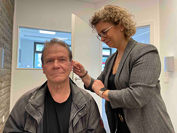 Bildbeschreibung: Die Gründerin Sabine Hönighausen passt in Fachgeschäft „Hörakustik Hönighausen“ einem männlichen Kunden sein Hörgerät an.