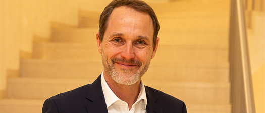 Bildbeschreibung: Auf dem Bild ist Gert Ettlmayr abgebildet. Er ist Vertriebschef und Senior Director Sales & Operations bei Geers. In beiden Händen hält er den Deutschen Service-Preis 2026. Ettlmayr ist mittleren Alters, er hat braune kurze Haare, eine hohe Stirn und einen graumelierten Bart und Schnurrbart. Er lächelt direkt in die Kamera. Er trägt einen schwarzen schicken Anzug und ein weißes Hemd.