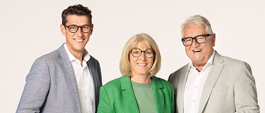 Bildbeschreibung: Auf dem Foto sind rechts die Eheleute Andrea und Peter Rottler abgebildet und links der Sohn Paul Rottler. Alle drei tragen Anzüge und Brillen. Frau Rottler ist ganz in Grün gekleidet.