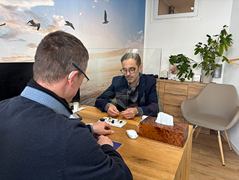 Bildbeschreibung: Auf dem Foto ist ein Hörakustiker in seinem Fachgeschäft zu sehen, der einem Kunden mehrere Hörsysteme vorstellt.